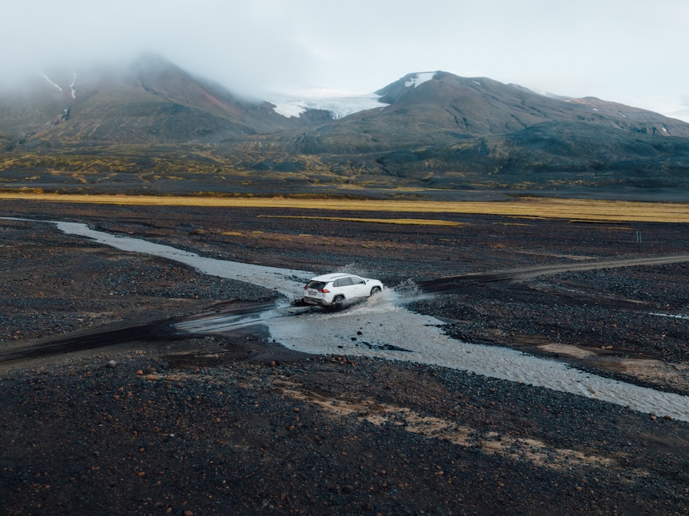 a white car driving through a puddle of water