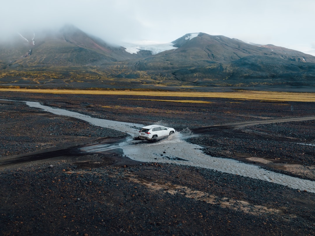 a white car driving through a puddle of water,