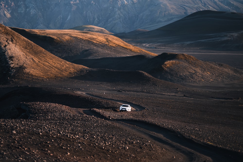 a car driving on a dirt road in the mountains
