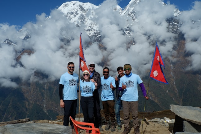 A group of friends wearing different styles of Traildry jackets smiling on a misty mountain summit.