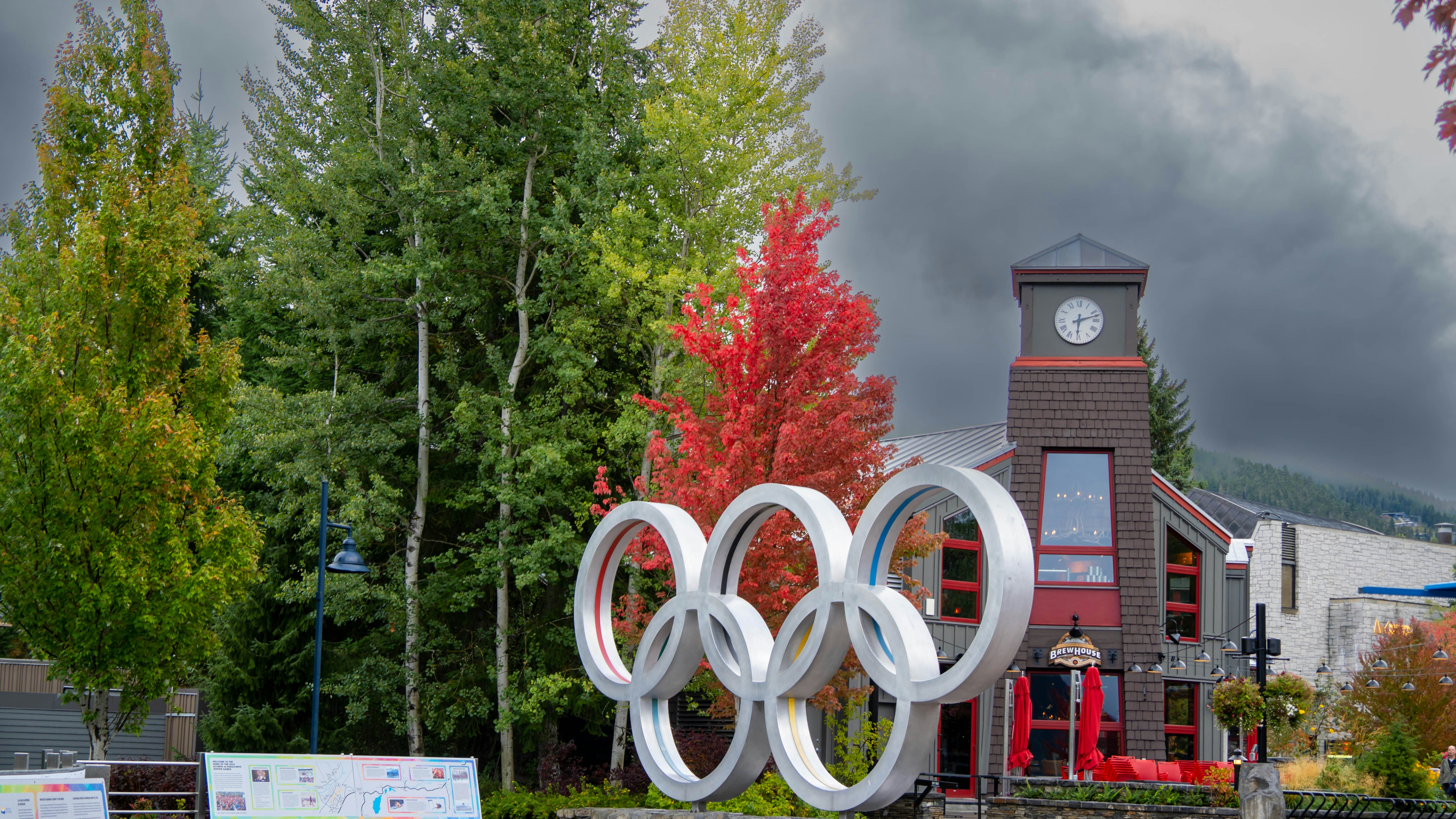 Sebuah menara jam berdiri di latar belakang sebuah bangunan dengan patung Olimpiade