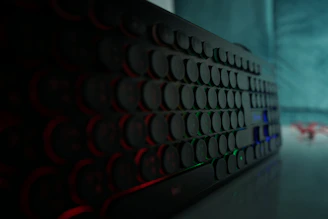 Close-up of a sleek mechanical keyboard with blue backlighting on a dark desk