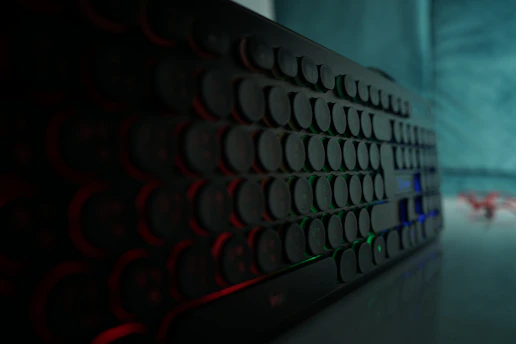 Close-up of a sleek mechanical keyboard with blue backlighting on a dark desk
