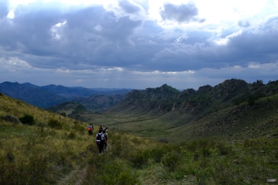 A small group walking together on a sunlit mountain trail, sharing a moment of connection.