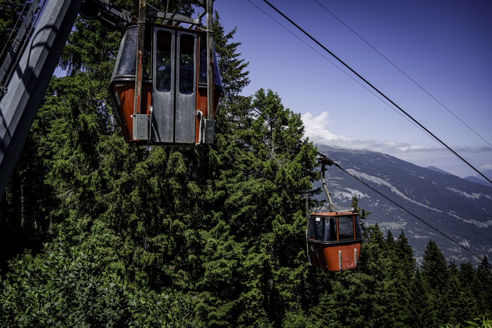 a couple of people riding a ski lift over a forest