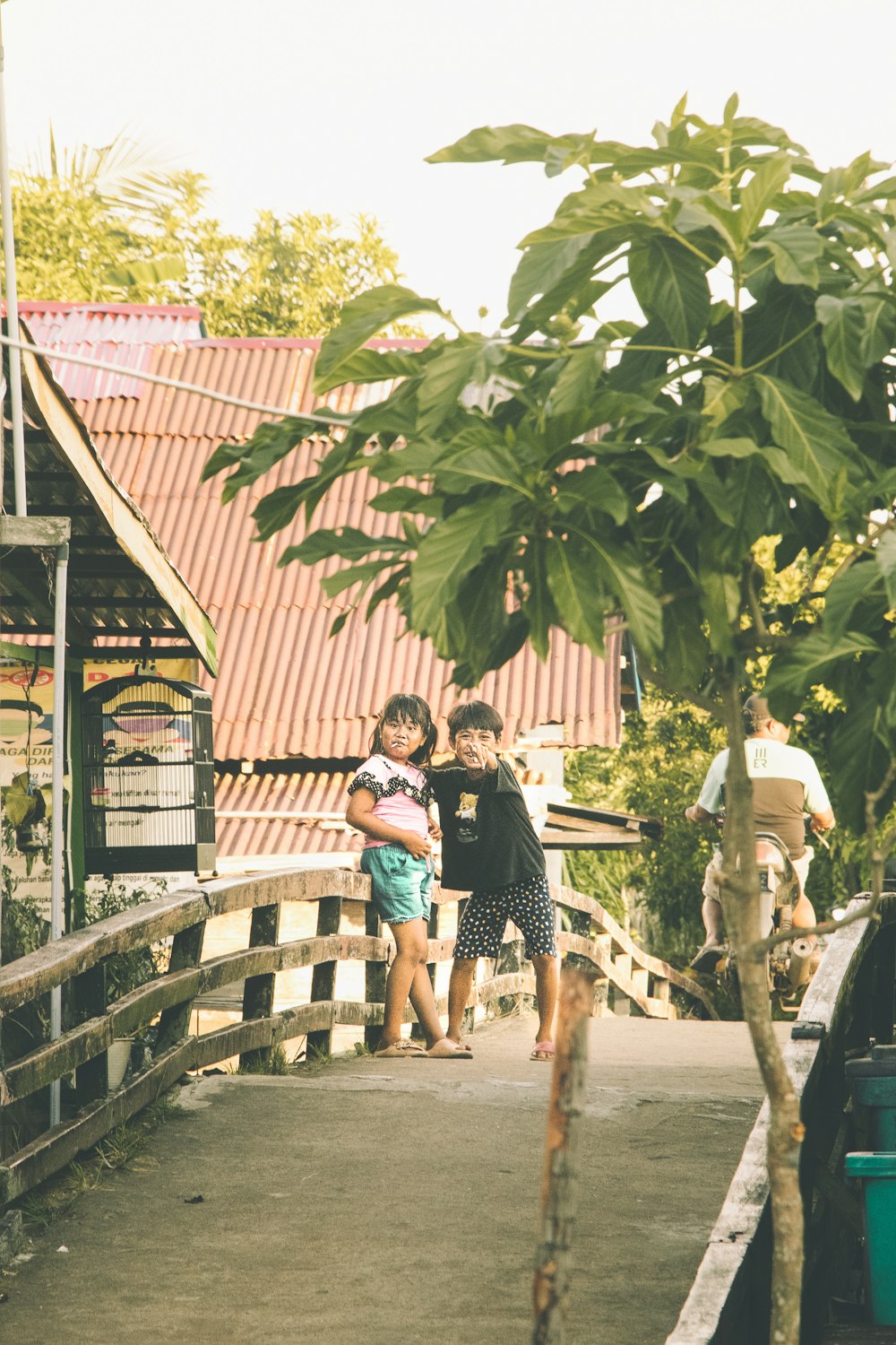 a couple of kids are standing on a bridge