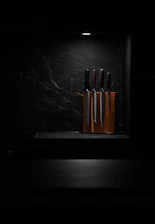 Elegant display of MARU JIN knives arranged on a minimalist wooden block highlighting their sleek design.