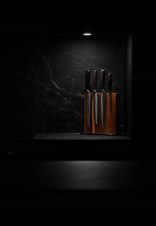 A set of polished steak knives arranged neatly on a rustic table with a warm background.