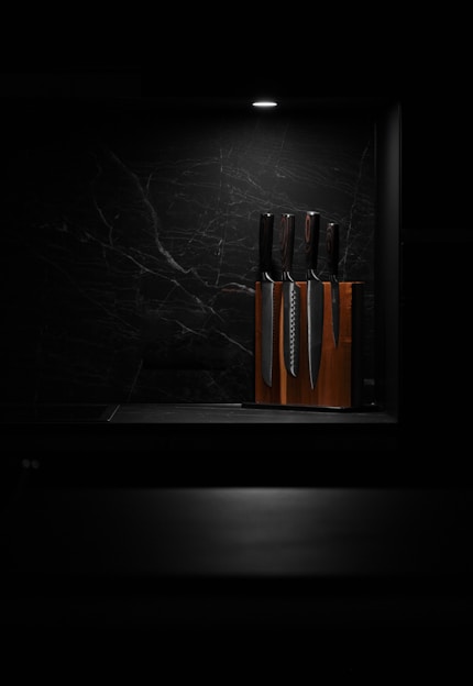 A sleek kitchen knife set displayed on a wooden cutting board with fresh vegetables around
