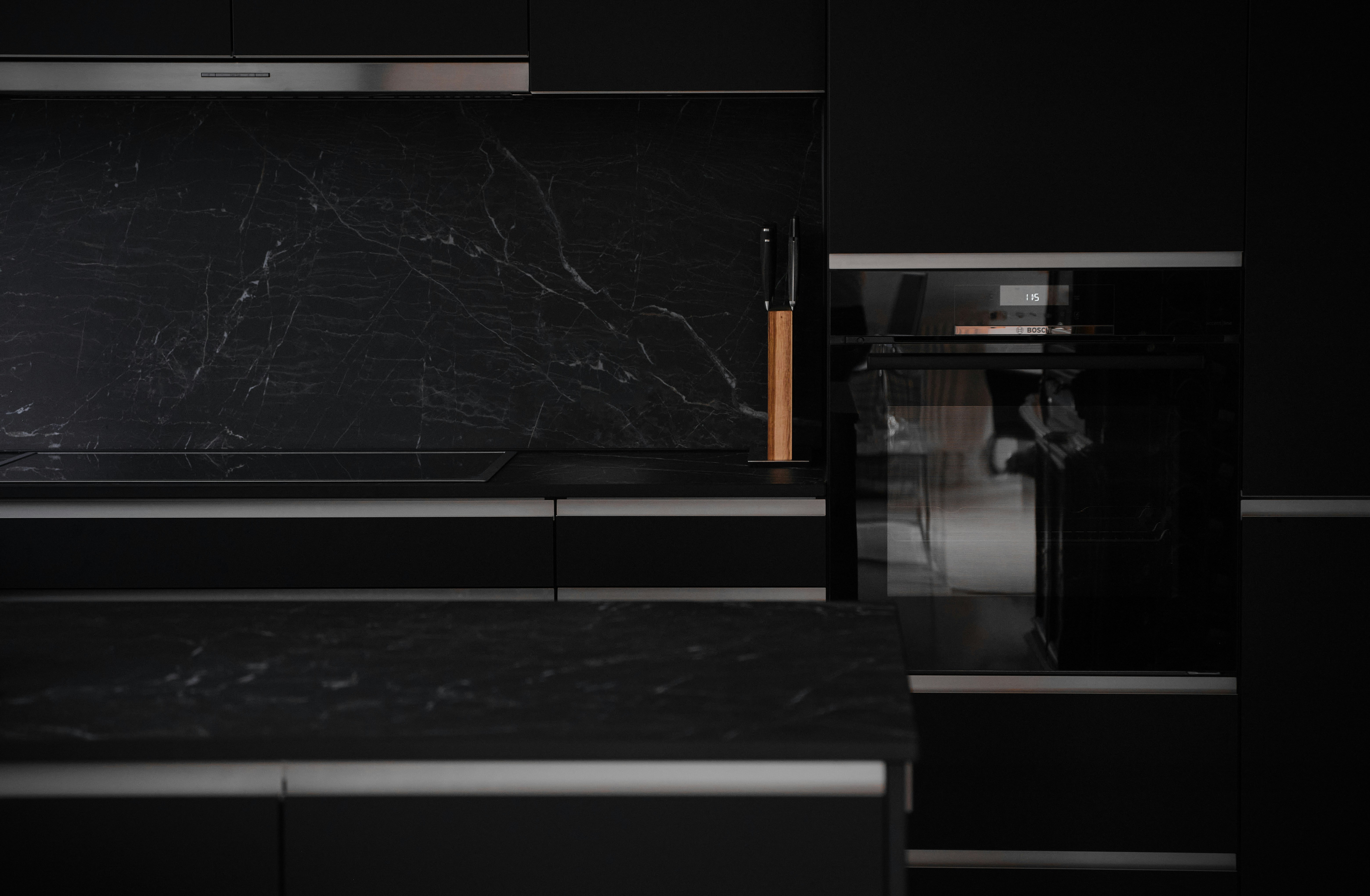 a black kitchen with marble counter tops and black cabinets