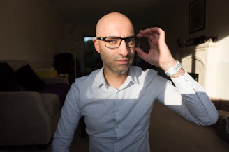 A cozy living room scene with a stylish person trying on premium eyeglasses during a home visit.