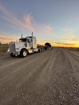 A weathered semi-truck parked under a vast Illinois sky at sunset, symbolizing the long journeys of truckers.