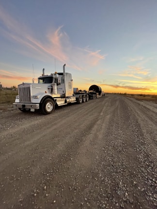 A sturdy flatbed trailer parked on a dusty Texas road at sunset.