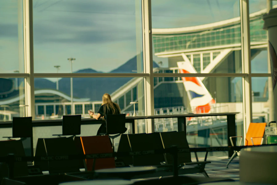 Traveler sitting at an airport terminal gate checking her phone while waiting to board