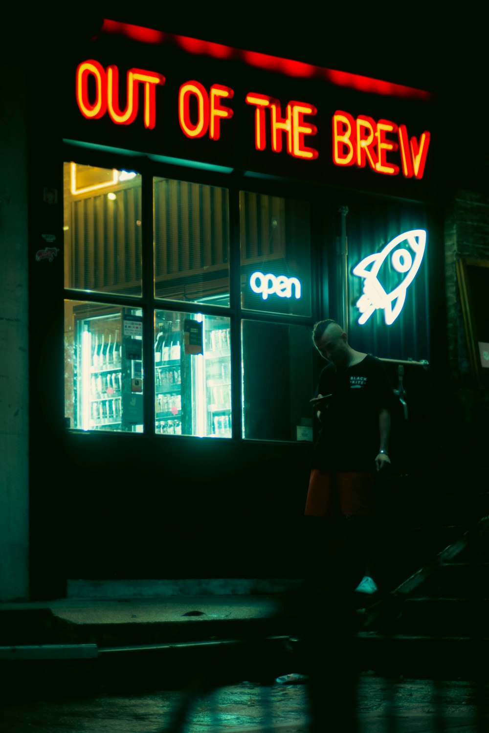 a man standing outside of a store at night