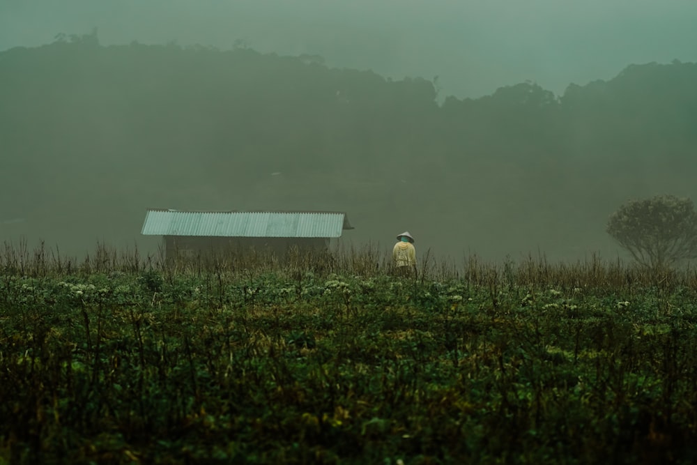 Una persona parada en un campo con un granero en el fondo