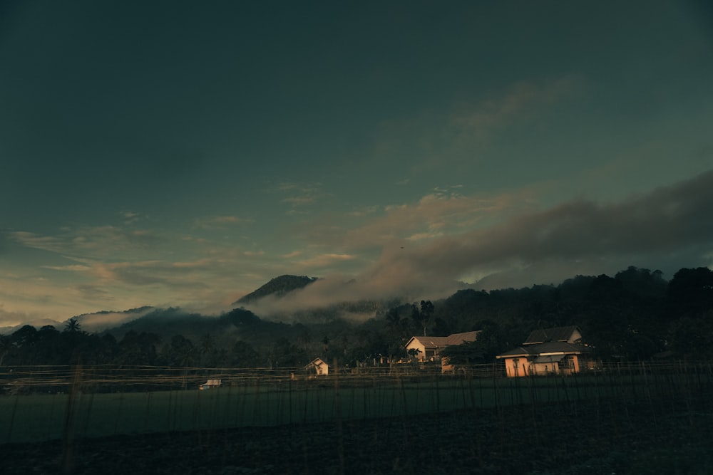 uma área cercada com uma casa e montanhas ao fundo