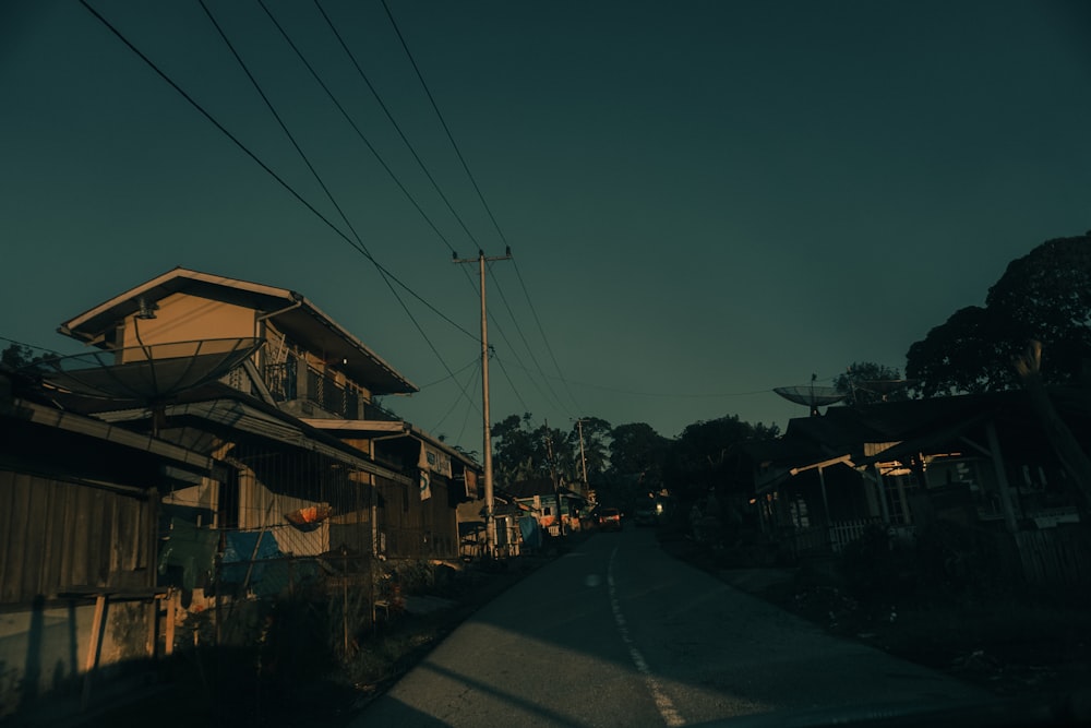 a dark street with houses and power lines