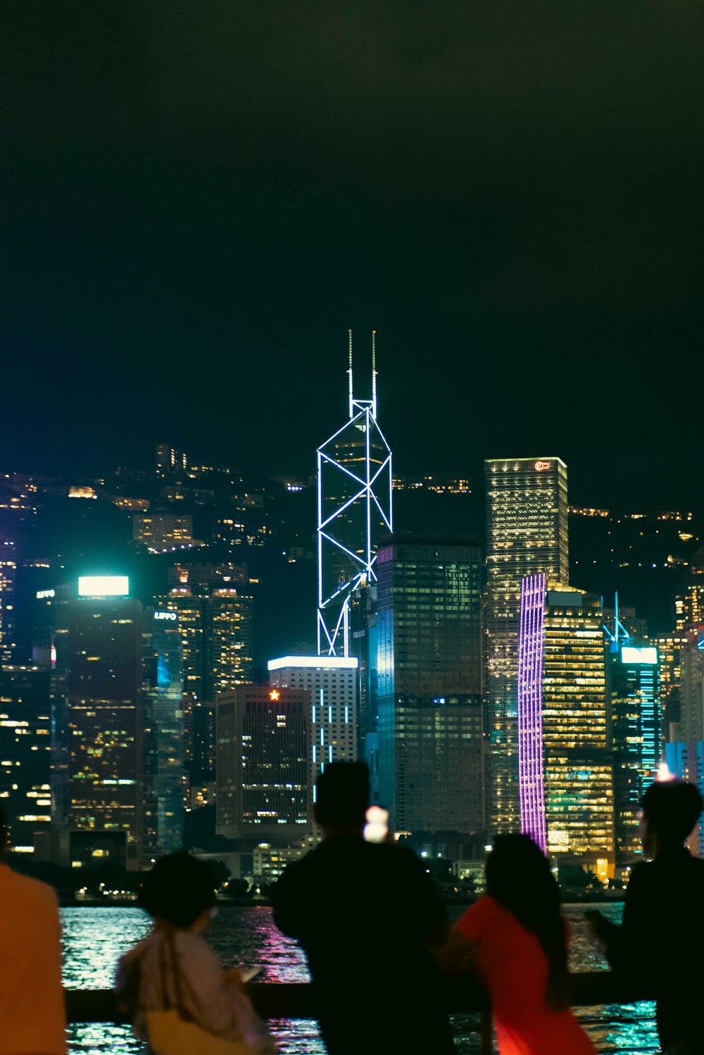 a group of people standing in front of a city at night