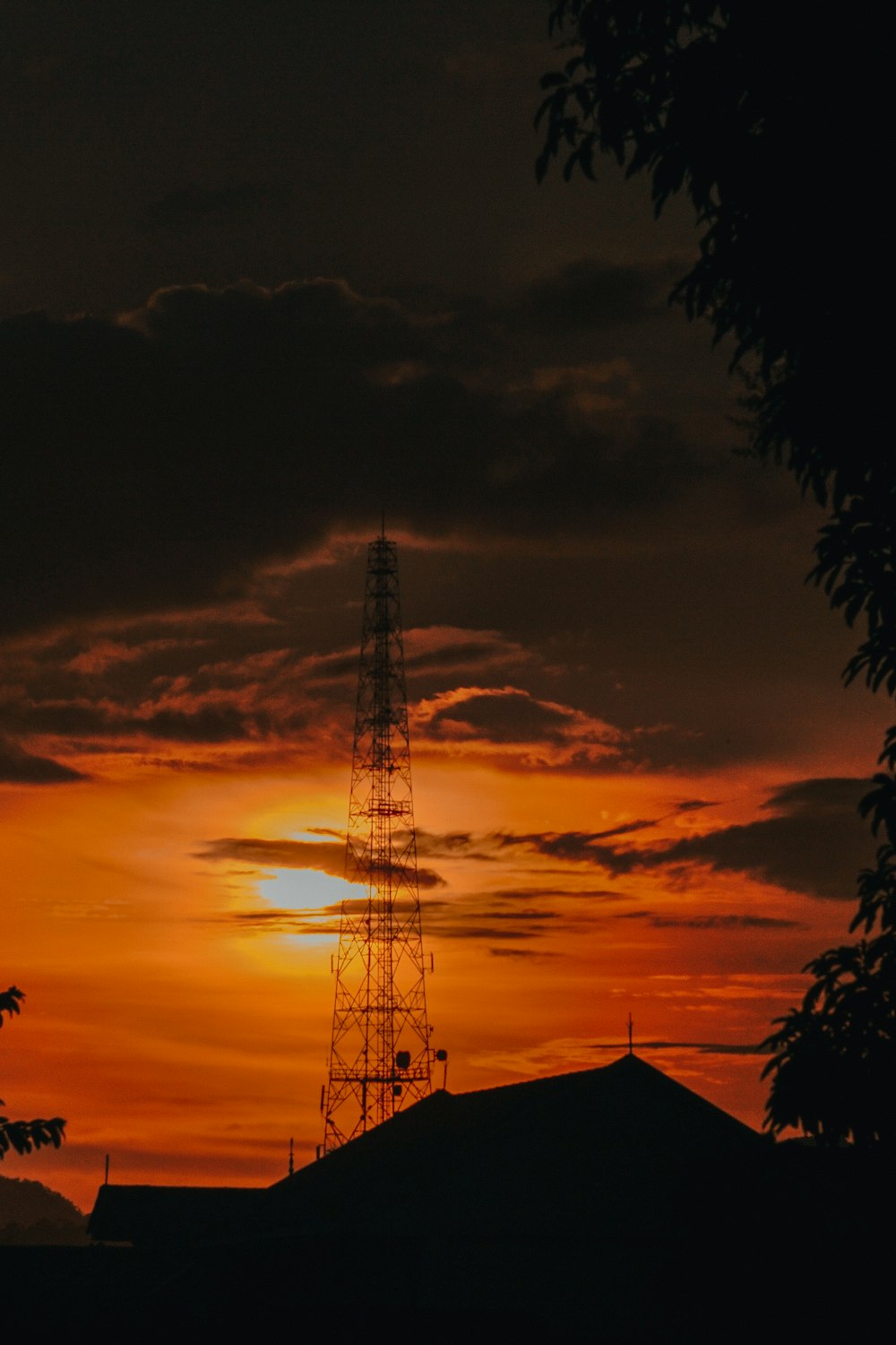 the sun is setting behind a radio tower