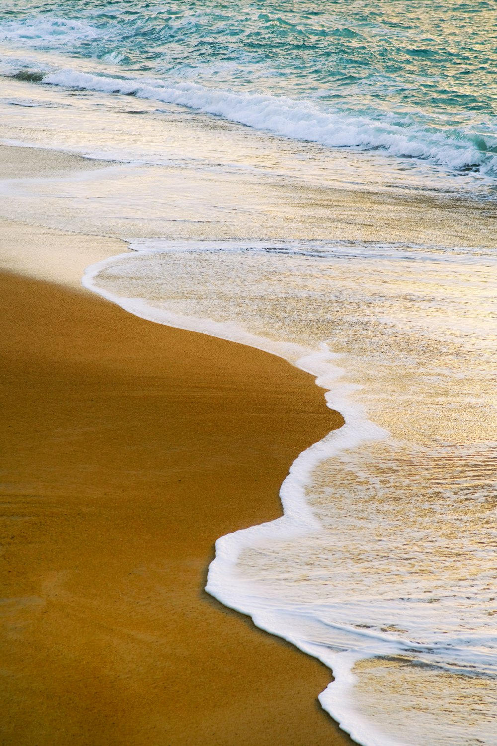 a sandy beach with waves coming in to shore