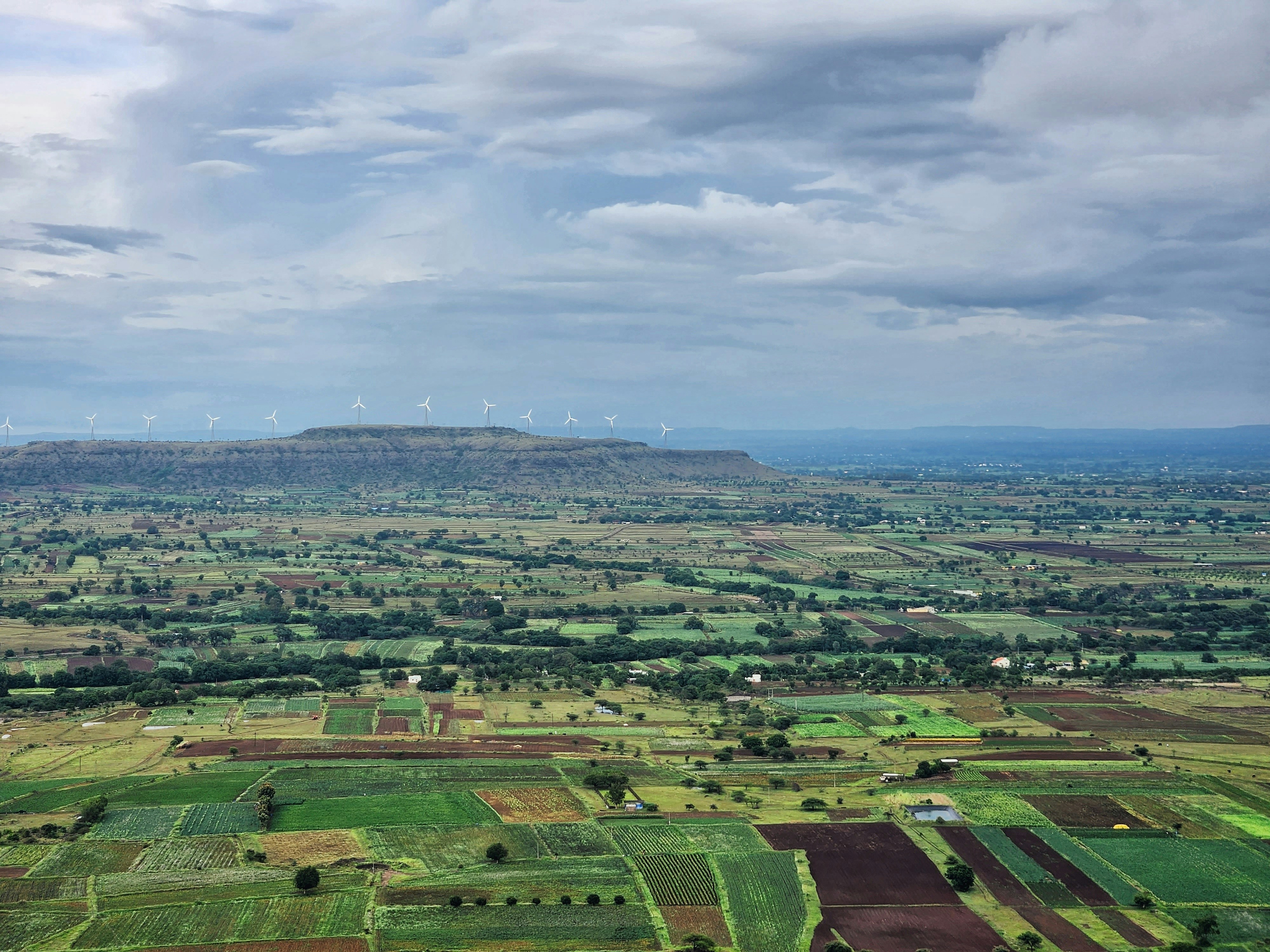 an aerial view of a field with a mountain in the background