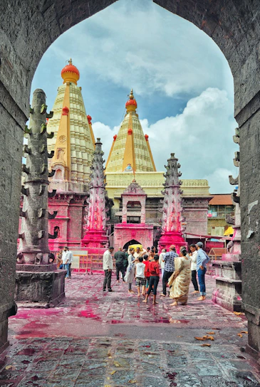 A vibrant group of pilgrims smiling on a sunny day beside the ancient Kashi Vishwanath Temple.