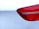 Close-up view of a car's rear light assembly with a shiny red plastic cover set against a smooth white car body.