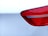 Close-up view of a car's rear light assembly with a shiny red plastic cover set against a smooth white car body.