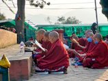 A volunteer teaching Vedic scriptures to a small group under a tree in the countryside.