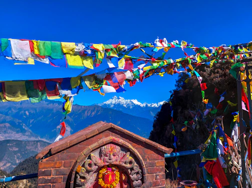 Sunlit Tibetan monastery perched on a mountain with prayer flags fluttering in the breeze.