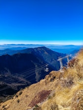A vibrant shot of the ropeway gliding over lush greenery near Odhni Dam, capturing adventure and heritage.
