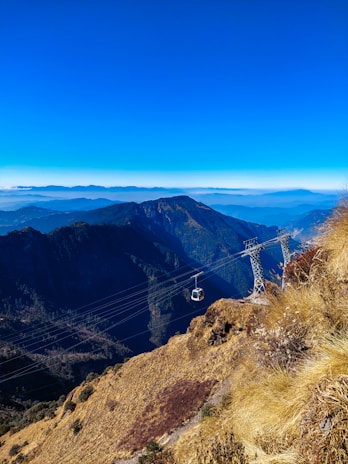 A vibrant shot of the ropeway gliding over lush greenery near Odhni Dam, capturing adventure and heritage.