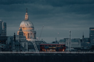 a red double decker bus driving past a tall building