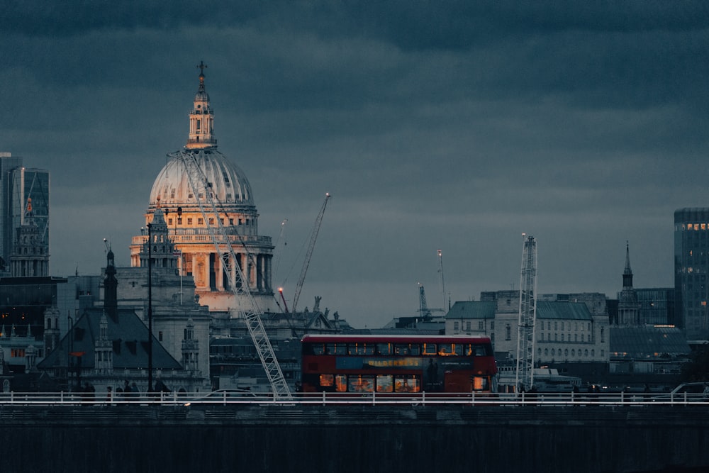 a red double decker bus driving past a tall building