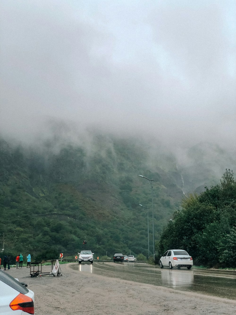 a group of cars driving down a rain soaked road