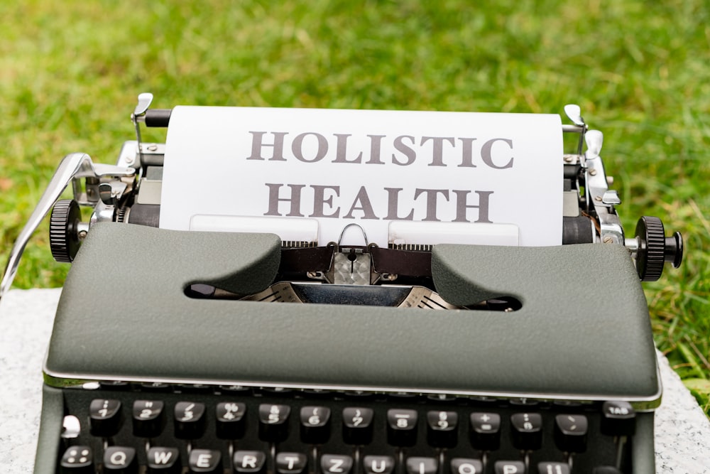 a close up of a typewriter with a paper that says holstic health