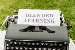 A vintage typewriter is placed on a surface with a grassy background, holding a sheet of paper with the words 'Blended Learning' typed on it.