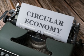 A vintage typewriter with a sheet of paper that has the words 'CIRCULAR ECONOMY' typed on it, set on a wooden surface.