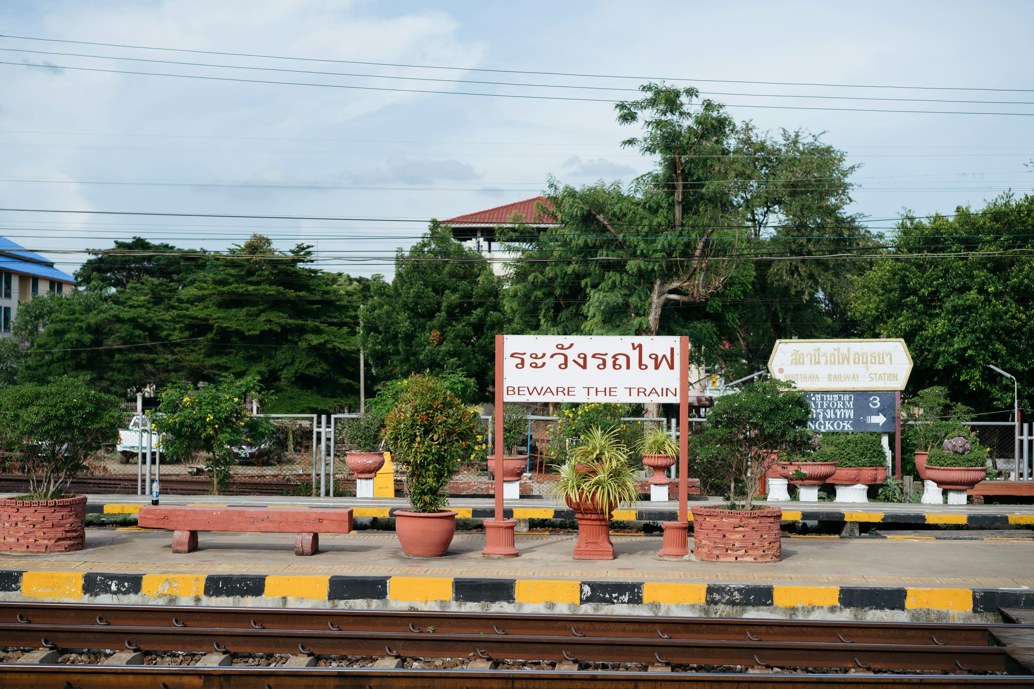 a train station with a sign and some plants