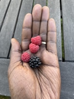Hand holding a bunch of mixed fresh berries over a wooden table