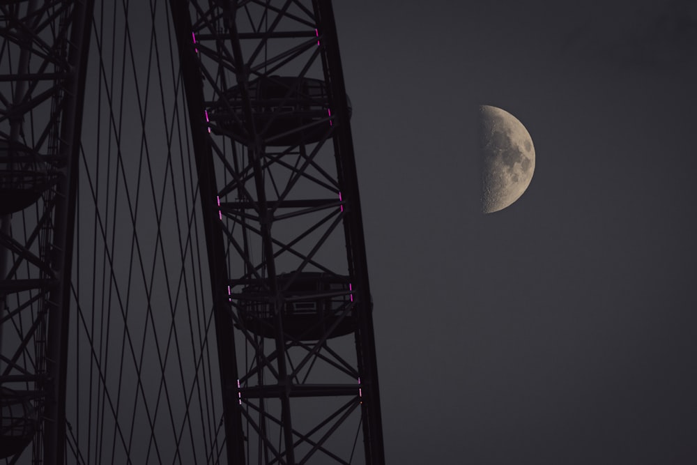 the moon is seen over the top of a bridge