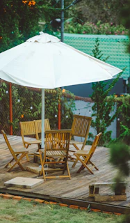 a wooden deck with a table and chairs under an umbrella