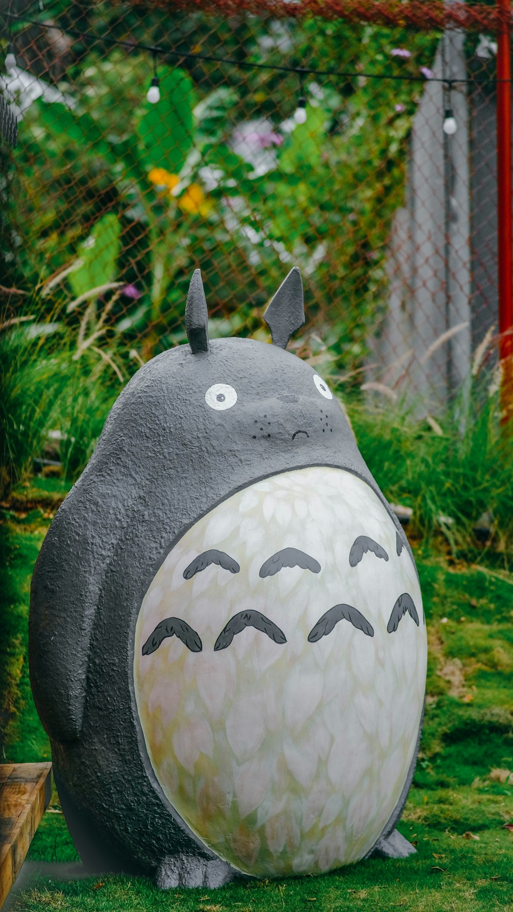 a statue of a totoro sitting in the grass