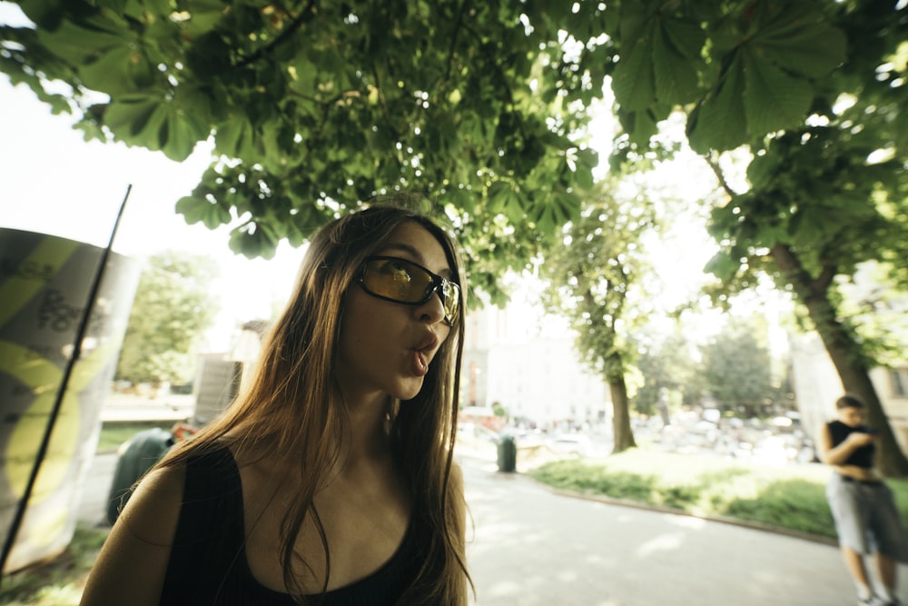 a woman standing under a tree in a park