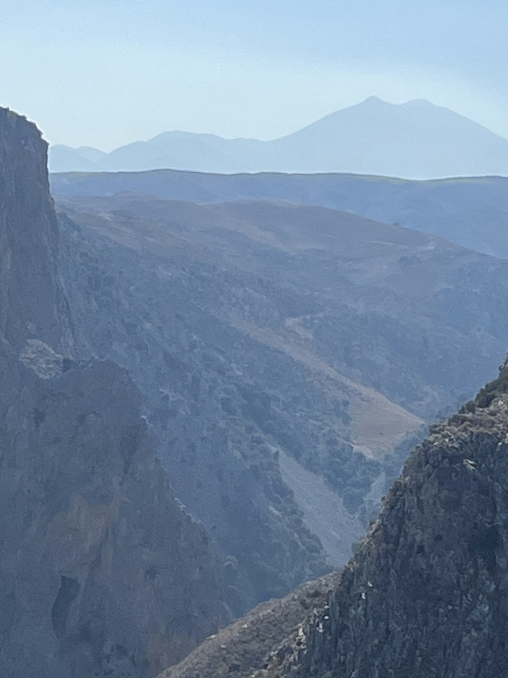 a man sitting on top of a mountain next to a sheep