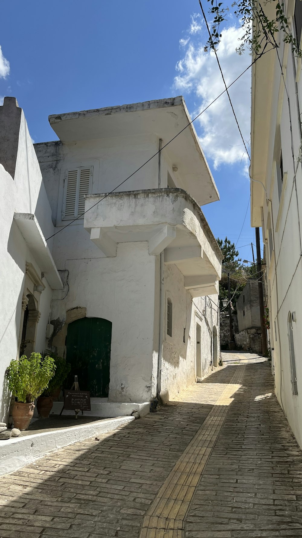 a white building with a green door on a brick street