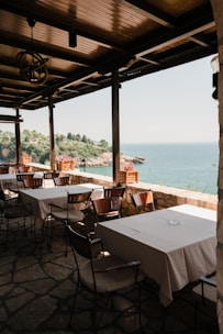 A serene beachside dining area with wooden tables and green plants.