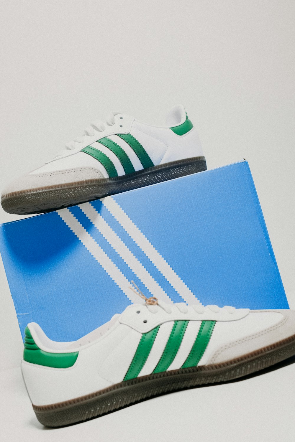 a pair of white and green adidas sneakers