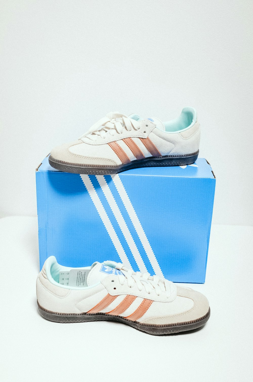 a pair of white and orange shoes sitting on top of a blue box
